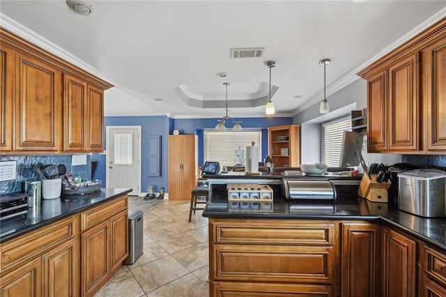 kitchen featuring light tile flooring, a healthy amount of sunlight, pendant lighting, and a tray ceiling