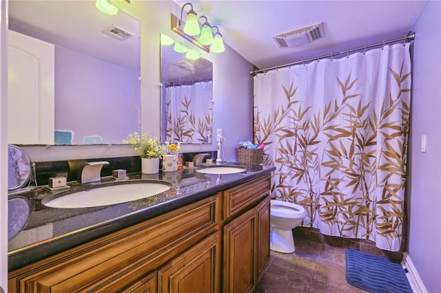 bathroom featuring toilet, vanity with extensive cabinet space, double sink, and tile flooring