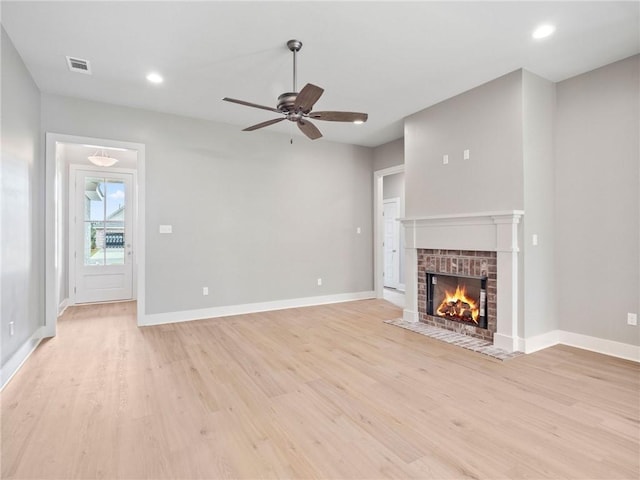 unfurnished living room featuring light hardwood / wood-style flooring, ceiling fan, and a fireplace