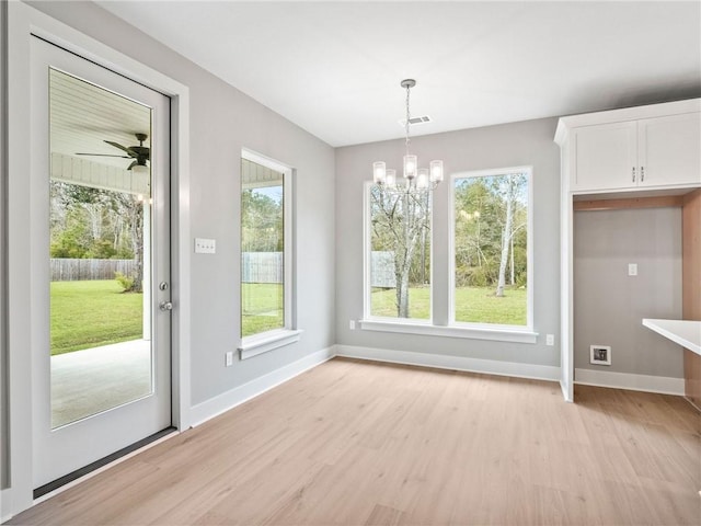 unfurnished dining area featuring ceiling fan with notable chandelier and light hardwood / wood-style floors