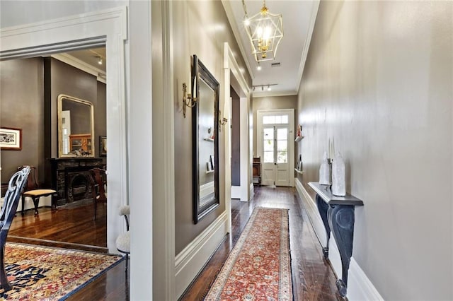 hall with an inviting chandelier, crown molding, and dark wood-type flooring