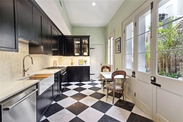 kitchen with appliances with stainless steel finishes, light tile floors, tasteful backsplash, and sink