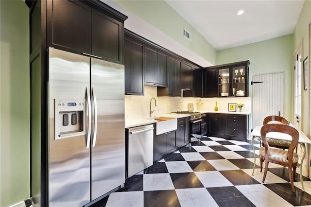 kitchen featuring appliances with stainless steel finishes, tasteful backsplash, dark tile flooring, sink, and dark brown cabinets