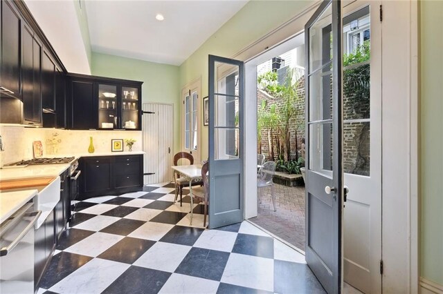 kitchen featuring stainless steel dishwasher, tasteful backsplash, and dark tile floors