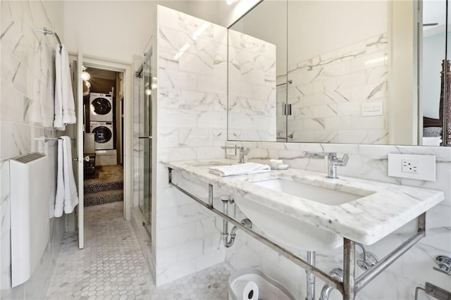 bathroom featuring tile flooring, dual vanity, stacked washer and clothes dryer, backsplash, and tile walls