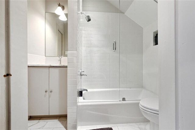 full bathroom with combined bath / shower with glass door, tile flooring, vanity with extensive cabinet space, and toilet