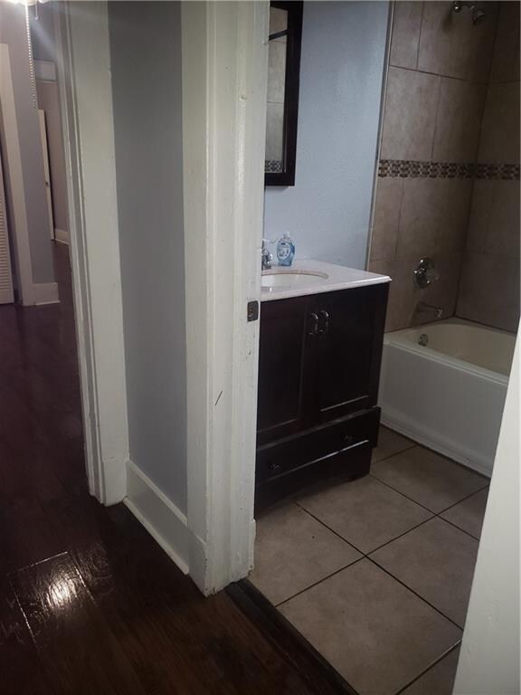 bathroom with vanity, tile flooring, and tiled shower / bath