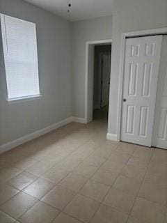 unfurnished bedroom featuring a closet and light tile floors