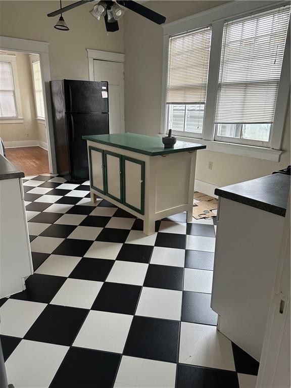 kitchen featuring black fridge, a wealth of natural light, and white cabinetry