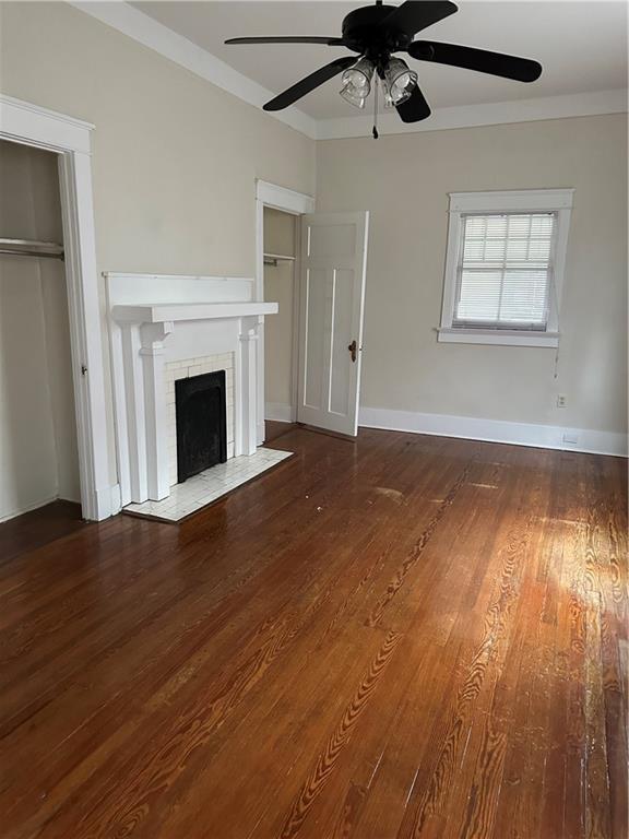 unfurnished living room with ceiling fan, dark wood-type flooring, and a fireplace