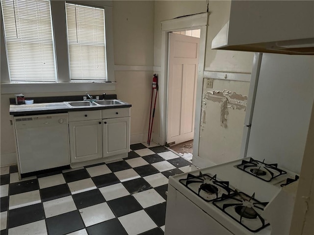 kitchen with wall chimney range hood, sink, white appliances, and white cabinetry