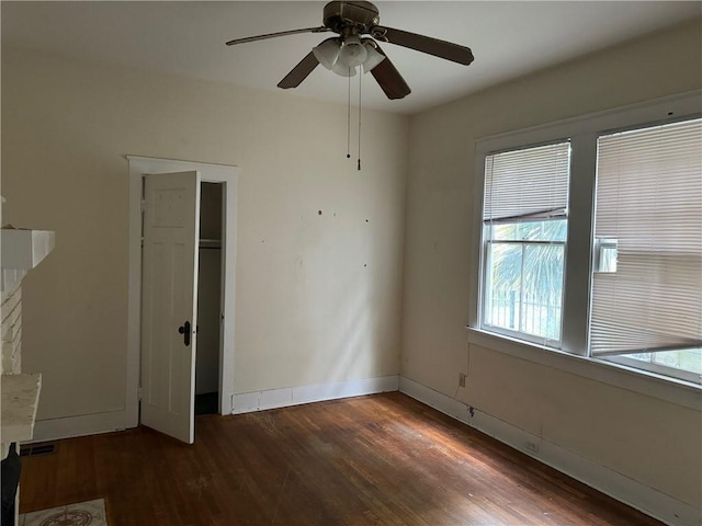 unfurnished bedroom featuring ceiling fan, a closet, dark hardwood / wood-style flooring, and a fireplace