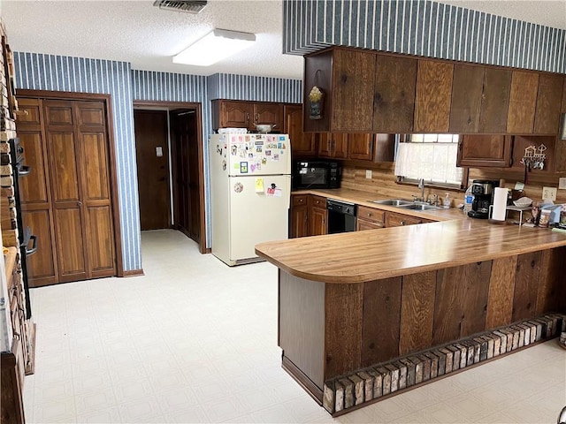 kitchen featuring sink, black appliances, kitchen peninsula, and a textured ceiling