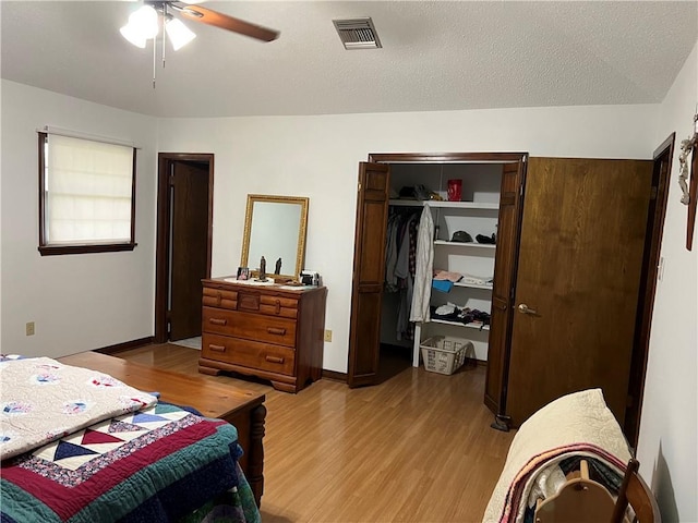 bedroom featuring ceiling fan, a closet, a textured ceiling, and light wood-type flooring