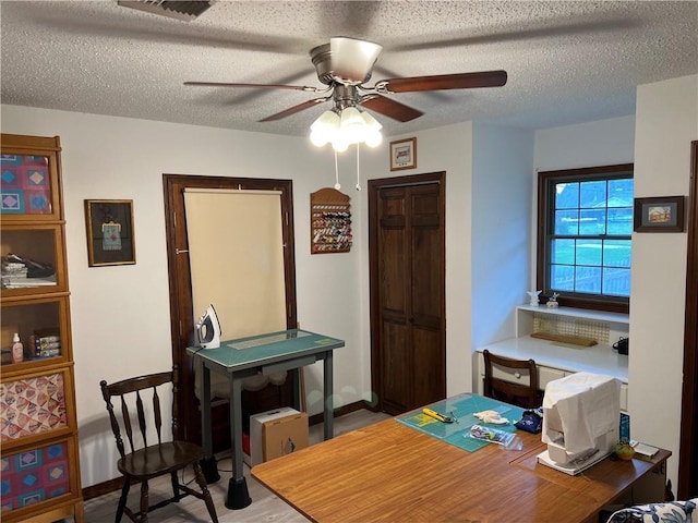 office area with ceiling fan and a textured ceiling