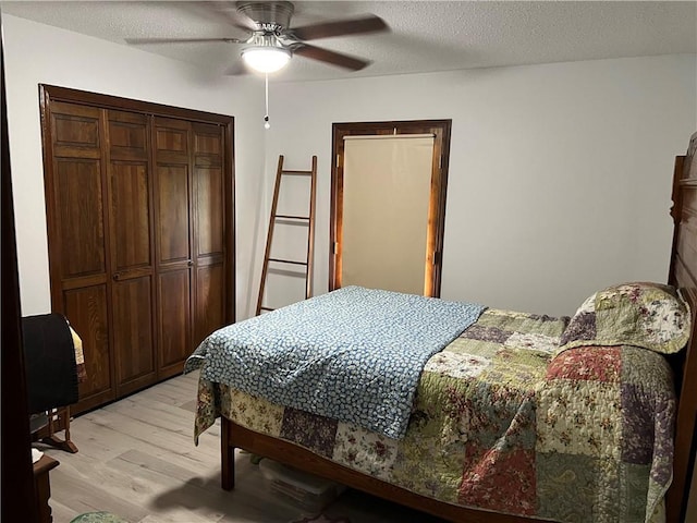 bedroom featuring ceiling fan, light hardwood / wood-style floors, a closet, and a textured ceiling