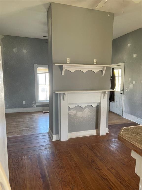 unfurnished living room featuring a towering ceiling, dark wood-type flooring, and ceiling fan