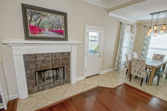 interior space with a tile fireplace, a chandelier, light hardwood / wood-style floors, and crown molding