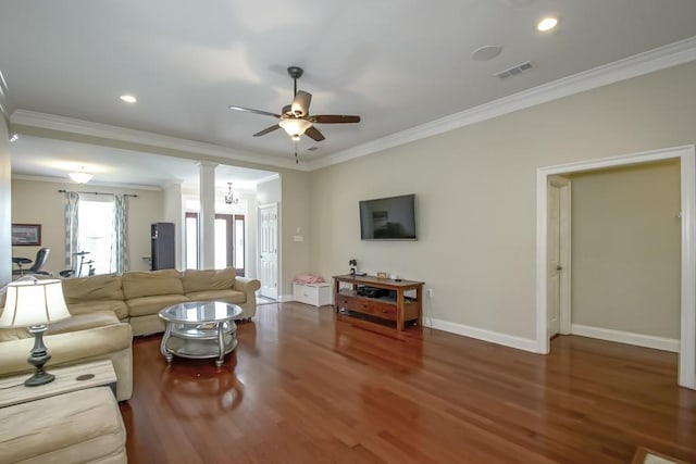 living room featuring ornamental molding, ceiling fan with notable chandelier, dark hardwood / wood-style floors, and ornate columns