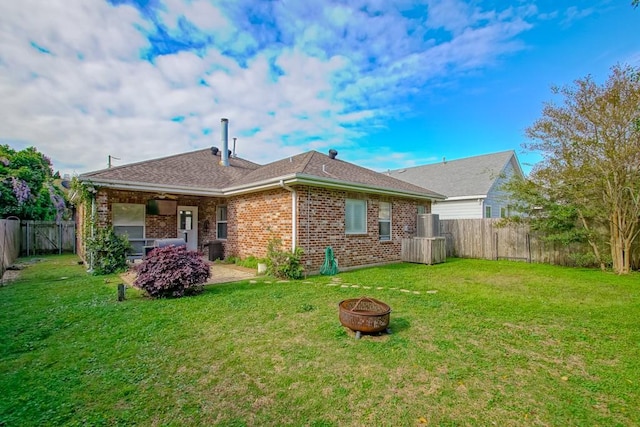 back of house featuring an outdoor fire pit and a yard