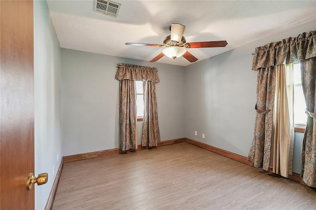 empty room featuring ceiling fan, light wood-type flooring, and a healthy amount of sunlight