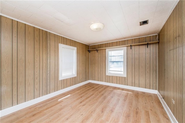 unfurnished room with wood walls and light wood-type flooring