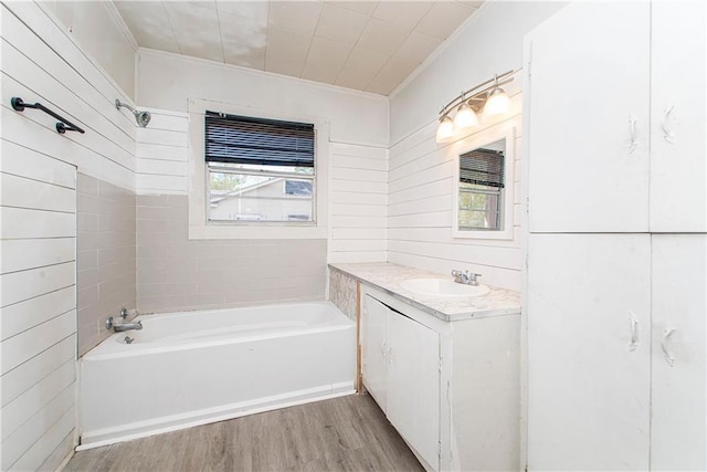 bathroom with hardwood / wood-style floors, ornamental molding, a bath, and large vanity