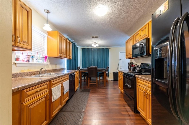 kitchen featuring pendant lighting, a textured ceiling, black appliances, dark hardwood / wood-style floors, and sink