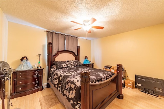 bedroom with a textured ceiling, ceiling fan, and light hardwood / wood-style flooring