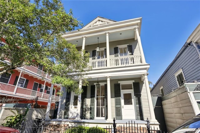 neoclassical home featuring a balcony and a porch