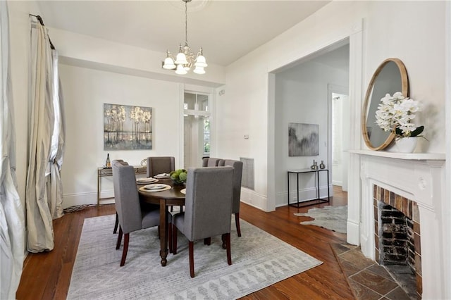 dining space with a tile fireplace, an inviting chandelier, and dark hardwood / wood-style flooring