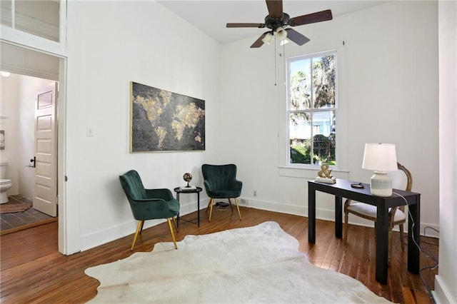 sitting room with ceiling fan and dark wood-type flooring