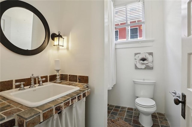 bathroom featuring toilet, sink, and tile flooring