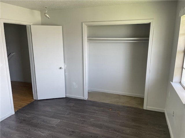 unfurnished bedroom with a closet, dark hardwood / wood-style floors, and a textured ceiling