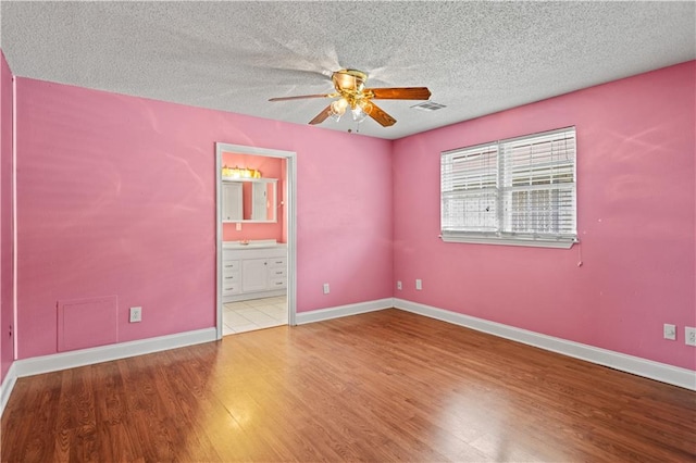 spare room with light hardwood / wood-style floors, ceiling fan, and a textured ceiling