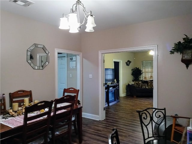 dining space featuring dark hardwood / wood-style floors and an inviting chandelier