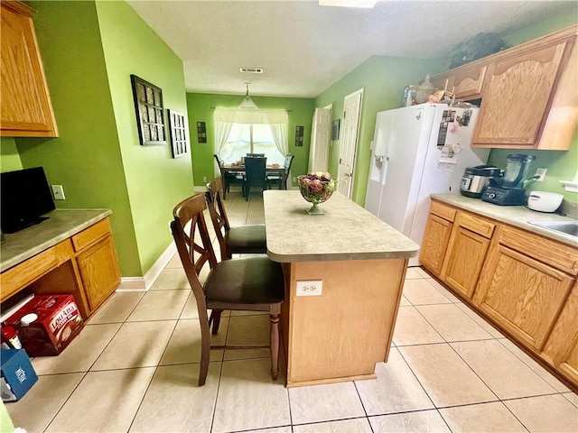 kitchen with hanging light fixtures, a center island, light tile patterned floors, and white refrigerator with ice dispenser