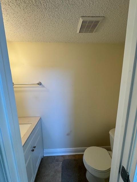 bathroom featuring toilet, a textured ceiling, vanity, and tile flooring