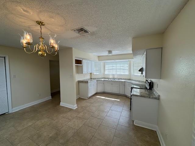 kitchen featuring a notable chandelier, light tile flooring, a textured ceiling, white cabinets, and hanging light fixtures