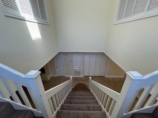 stairway featuring dark carpet