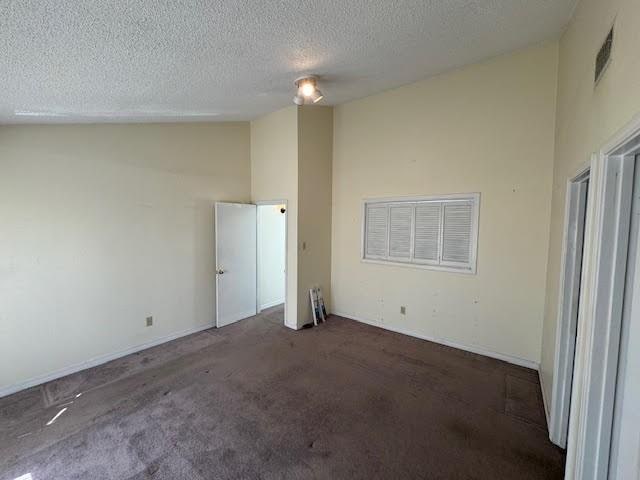 unfurnished room with high vaulted ceiling, a textured ceiling, and dark colored carpet