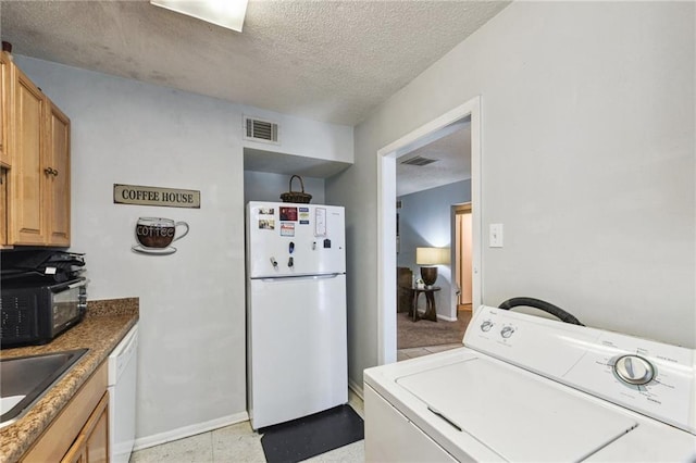 clothes washing area with sink, washer / dryer, light tile floors, and a textured ceiling