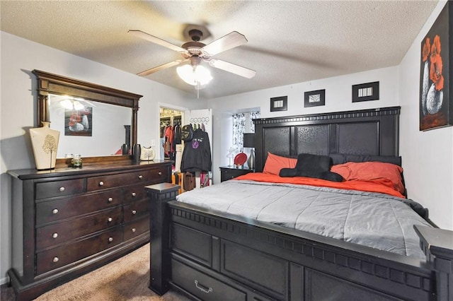 carpeted bedroom featuring a spacious closet, a closet, ceiling fan, and a textured ceiling