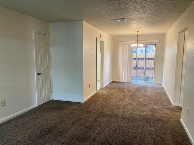 unfurnished room featuring a textured ceiling, dark carpet, and a chandelier