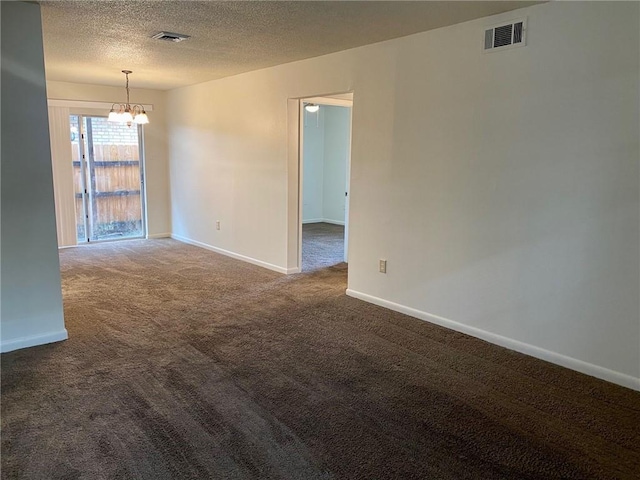 carpeted empty room featuring a chandelier and a textured ceiling