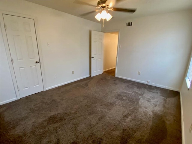 spare room featuring ceiling fan and dark colored carpet