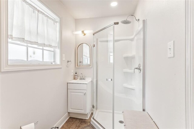 bathroom featuring a shower with door and vanity