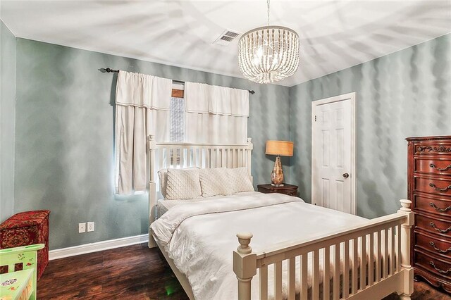 bedroom with dark hardwood / wood-style flooring and an inviting chandelier