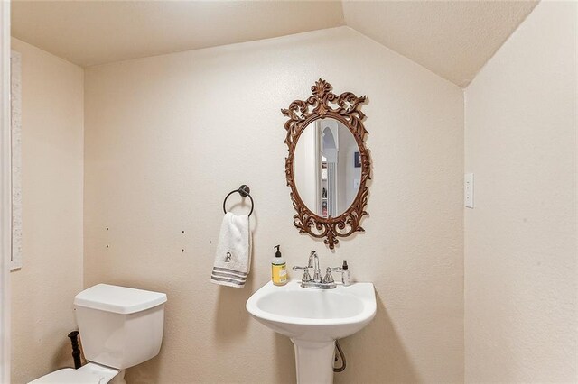 bathroom featuring sink, toilet, and lofted ceiling