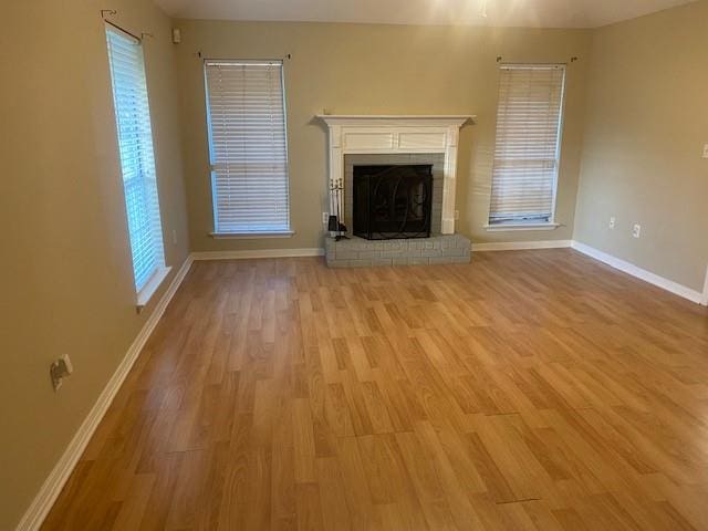 unfurnished living room with a brick fireplace and light hardwood / wood-style flooring